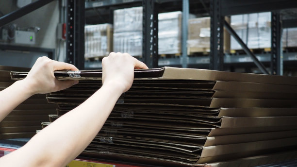 仓库大型仓储或物流或货物配送。男人的手正拿起一个盒子。图片下载