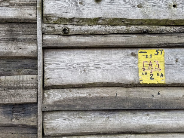 用木板水平切割而成的巨大栅栏。下面是黄色天然气管道标志。树的一年生条纹的纹理背景图片。图片下载