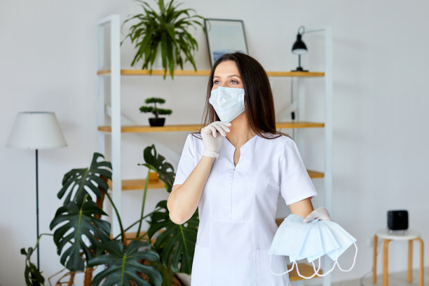 女性医护专业人员示范正确佩戴口罩，以保护自己免受冠状病毒感染。近距离观察正在穿戴安全设备的女医护人员图片下载