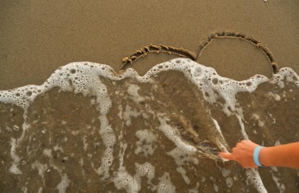 女人在沙滩边手绘心形图片下载