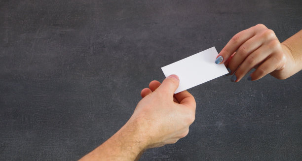 一个男人和一个女人交换名片。手的特写视图。灰石的背景。图片下载