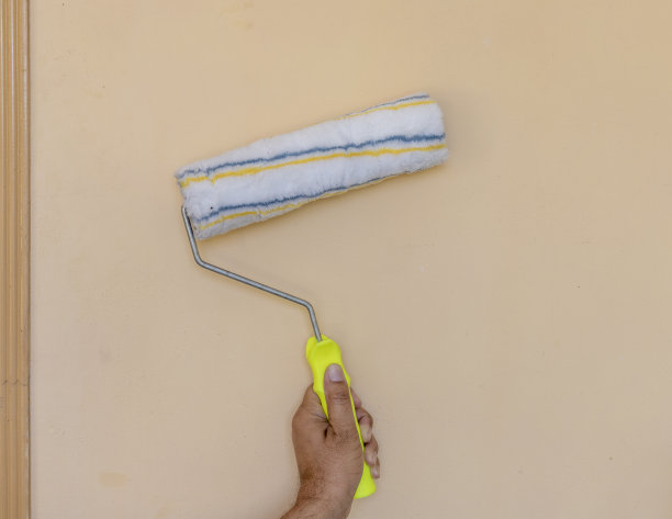 手握滚筒漆刷在墙上图片下载