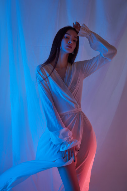 艺术美丽的女人在吹飞扬的衣服。霓虹灯中的自由概念。时尚风格的飘逸的衣服在身体的女人。飘舞的裙子在风中飘扬图片下载