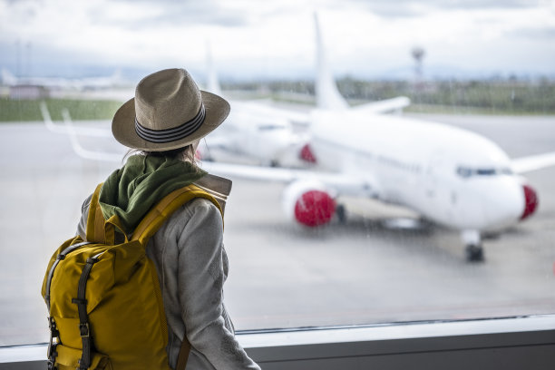 一名女子在机场等飞机时使用手机。在户外看飞机。图片下载
