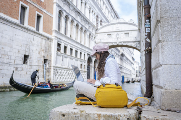 女人在威尼斯度假时用笔记本电脑工作。图片下载