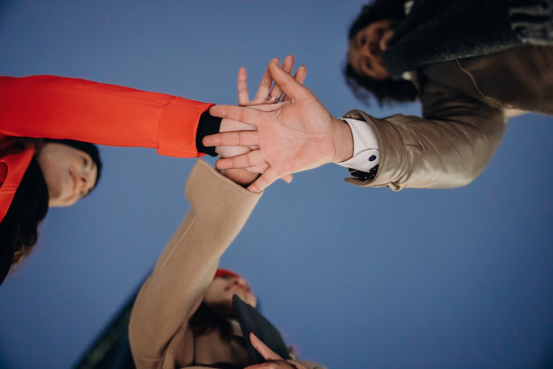 三个商务人士手牵手放在中间，团队合作，低角度视角图片下载