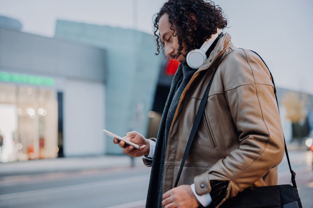 傍晚，商人站在人行道上，一边用手机一边微笑图片下载