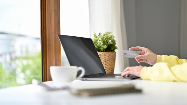 特写图片，女性手持信用卡，使用笔记本电脑。图片下载