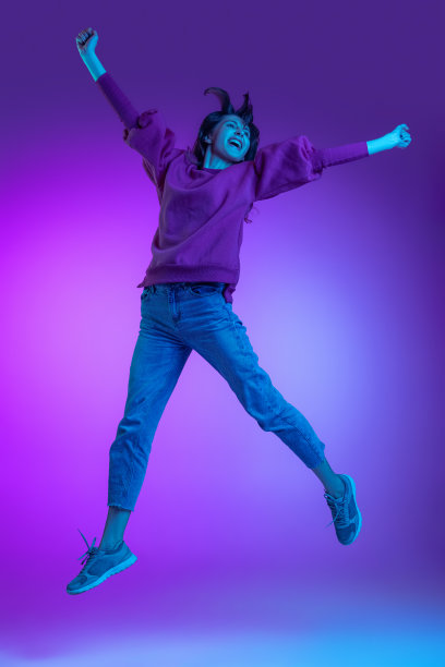全身肖像年轻兴奋的女孩，学生跳跃孤立的紫色背景在霓虹灯。情感的概念，面部表情，艺术，美图片下载