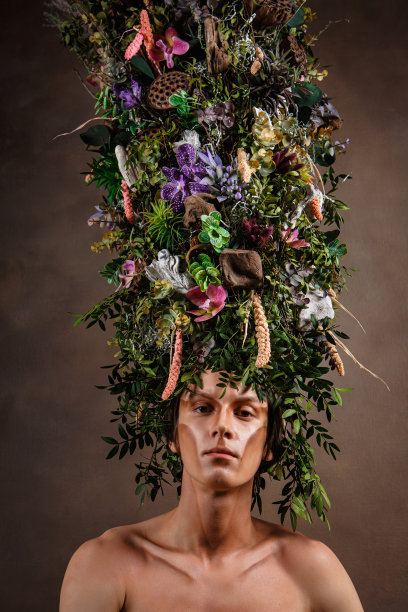 戴着由多种植物和花卉制成的巨大细长头饰的男子。自然之子，神奇的生物。艺术对象图片下载