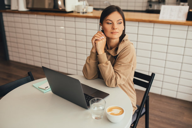 年轻的自由职业者，在一个舒适的咖啡馆里用笔记本电脑喝着咖啡，在网上工作。图片下载
