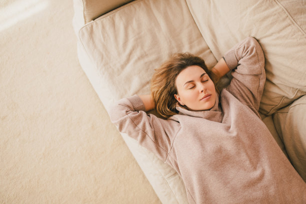 一个年轻女人在舒适的房子里的沙发上放松。图片下载