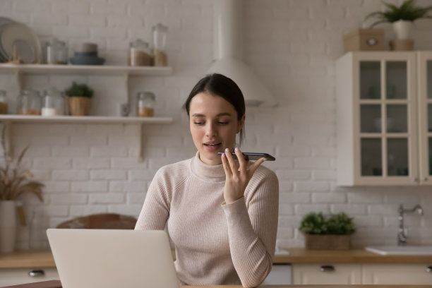 女人在笔记本电脑上工作，用扬声器与客户通话图片下载