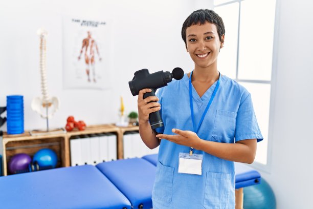 年轻的西班牙妇女穿着物理治疗师制服，在家里握着打击手枪图片下载