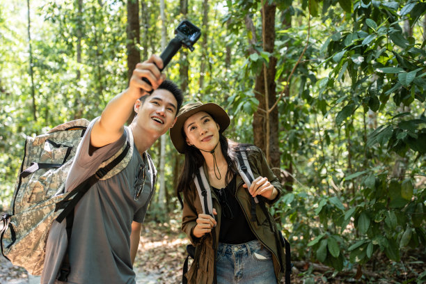 亚洲年轻夫妇背包客视频博主独自在森林里旅行。有魅力的男女旅行者用相机记录视频视频，在大自然的树林里散步，在假期快乐的旅行。图片下载