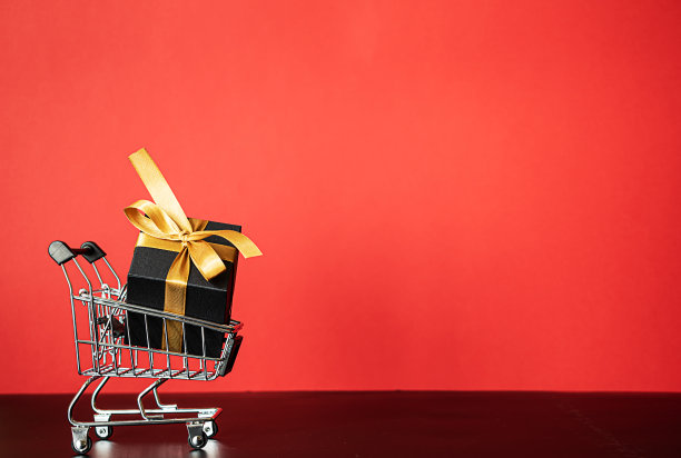 一辆小车站在红色的背景上，车上有一个带着金丝带的礼品盒图片下载