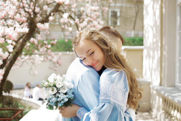 甜蜜的情侣在盛开的木兰树下拥抱。背景是复古别墅图片下载