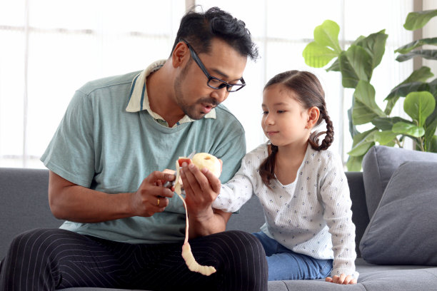 父亲为生病的女儿削苹果：照顾生病女儿，父亲节快乐图片下载