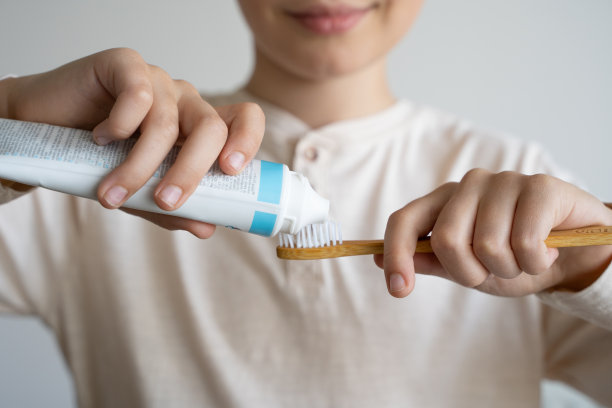 特写肖像儿童挤出白色牙膏到环保牙刷图片下载