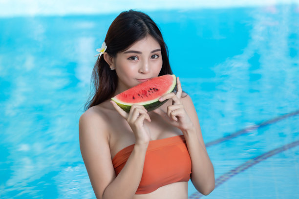 穿着比基尼的美女在泳池边喝着鸡尾酒放松。图片下载