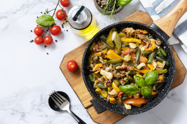 素镬翻炒。大理石桌面上有海鲜虾仁、鱿鱼、墨鱼，配以蔬菜和大蒜酱。俯视图平lay。副本的空间。图片下载