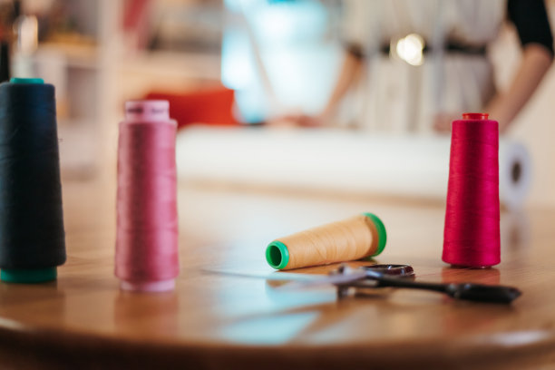 车间工作台上摆各色缝纫线盘图片下载