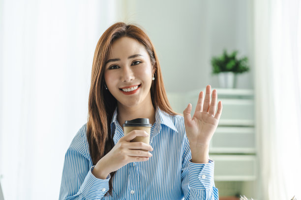 有魅力的亚洲女商人看着镜头举起手打招呼。图片下载