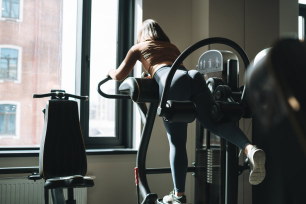 年轻的褐发女性健身训练腿部肌肉设备在健身房图片下载