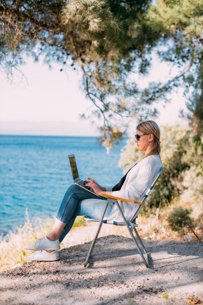 金发女人在度假的海滩上用笔记本电脑工作图片下载