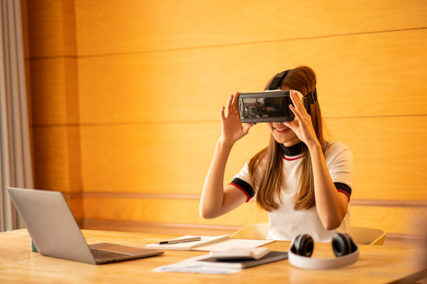 快乐的白人女性戴着虚拟现实眼镜在家里女孩玩与眼镜与手在设备上做出想象的手势。图片下载