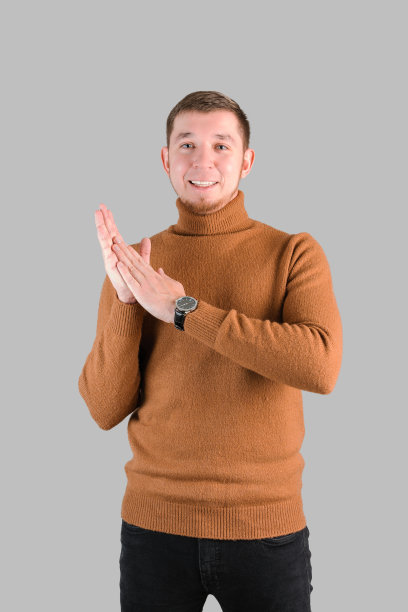 一名身穿红色毛衣、留着胡子的潮人站在一张灰色背景的垂直照片上拍手图片下载