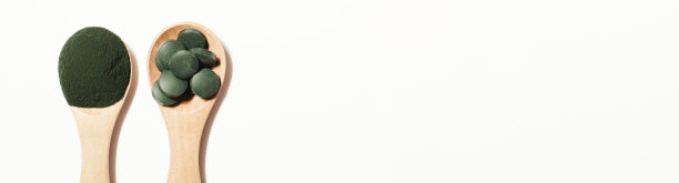 天然添加剂和超级食品。白色背景木勺上的绿色螺旋藻粉和药丸。健康的有机的概念。横幅复制空间图片下载