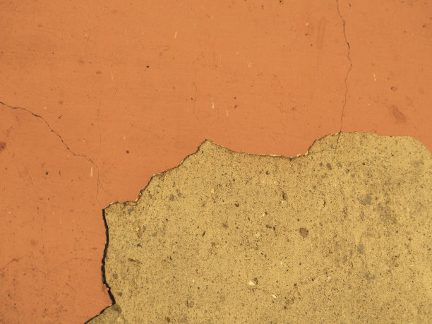 混凝土墙上橙黄色的灰泥。一堵旧漆墙的垃圾背景。旧墙表面的纹理图片下载
