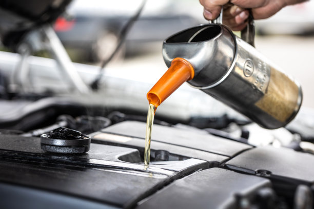 汽车修理厂机械师在汽车维修过程中添加机油的特写图片下载