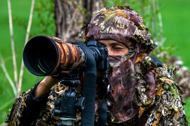 一名女性自然摄影师隐藏着等待动物。图片下载