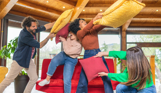 快乐的多元文化朋友在客厅里玩枕头大战图片下载