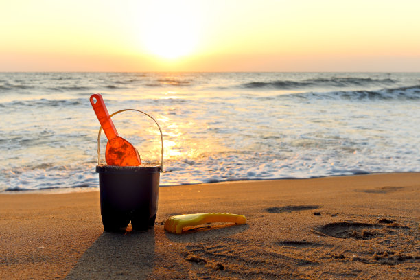 沙滩上的沙滩玩具，用于在日落时分在海边建造沙堡，热带岛屿的暑假图片下载