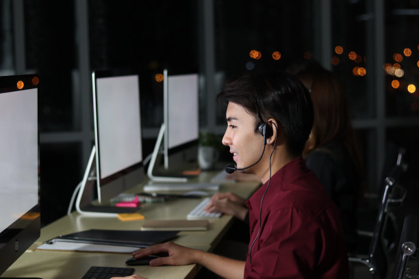 快乐的亚洲男人在呼叫中心服务台与队友一起工作图片下载