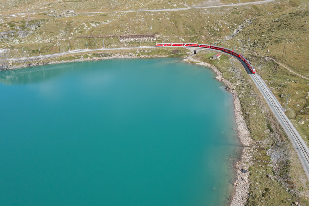 无人机拍摄的瑞士火车经过伯尼纳山口的比安科湖，瑞士Grisons图片下载