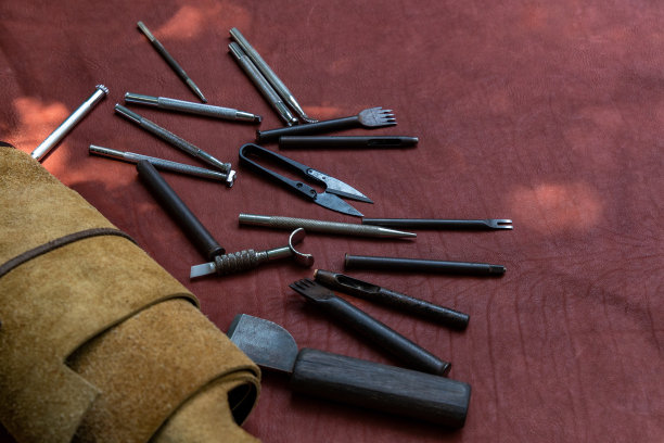 工具和皮革工作场所。套皮革工艺工具，皮革工匠办公桌上的鞣制皮革，皮革工匠的工作过程。图片下载