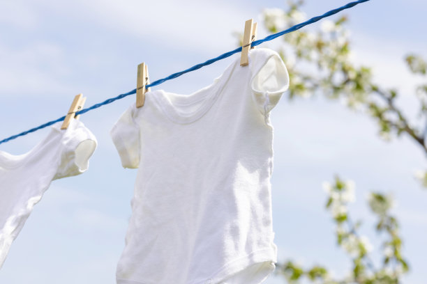 春天，白色的婴儿衣服挂在户外的绳子上图片下载