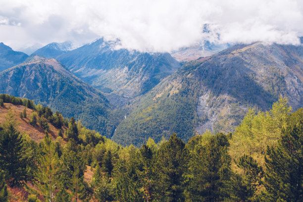 山间的美景如画。令人惊叹的山脉山谷风景景观之间的云和古色古香的森林丘陵。山间秋色摄影素材图片下载