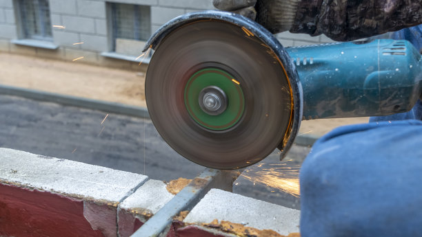 近景的工人与角磨床工作。钢结构电动砂轮磨削。火花。图片下载