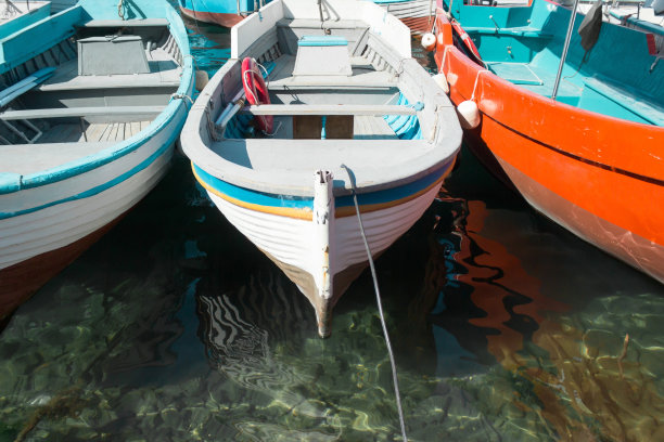 阳光明媚的日子，旧木船停在干净的水面上图片下载