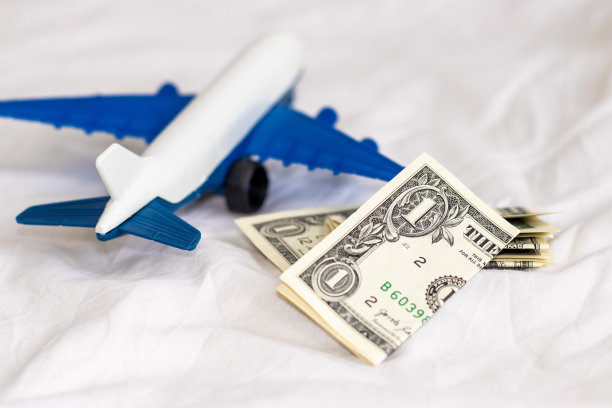 白色毯子上有飞机，美元和欧分硬币。旅游理念，旅游，与家人朋友一起旅游。预订机票。旅行社、广告横幅。节约钱,图片下载