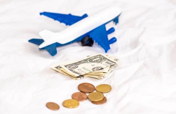 白色毯子上有飞机，美元和欧分硬币。旅游理念，旅游，与家人朋友一起旅游。预订机票。旅行社、广告横幅。节约钱,图片下载