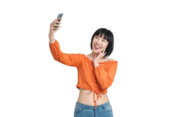 年轻的亚洲女性正在用她的智能手机自拍，孤立。图片下载