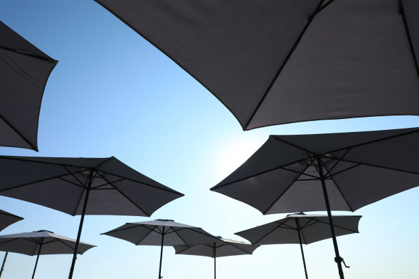 阳光明媚的日子里，海滩上的遮阳伞遮挡着蓝天图片下载