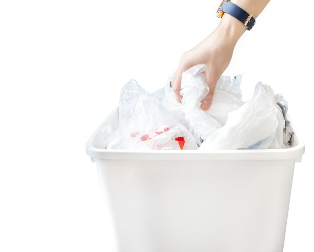 人们用手把干净的塑料袋放在白色背景的回收箱里。图片下载