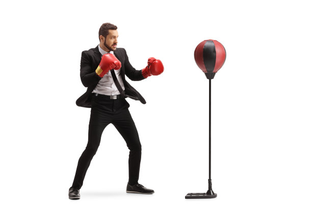 一个商人的全长镜头与拳击手套锻炼与一个自由站立沙袋图片下载